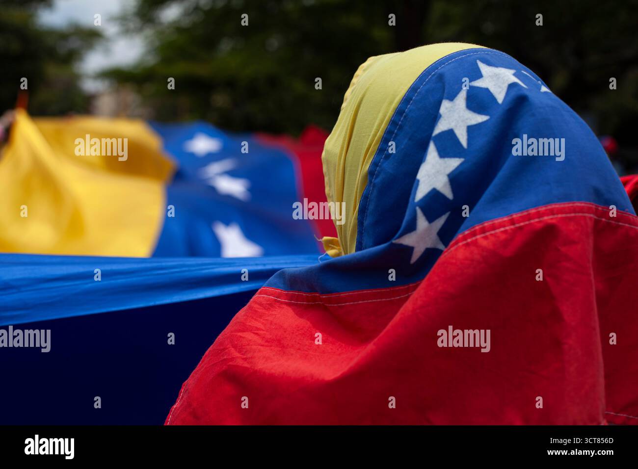 Flaggen Venezuelas. Eine nicht erkennbare menschliche Figur trägt eine venezolanische Flagge auf dem Kopf. Stockfoto Flaggen Venezuelas. Eine nicht erkennbare menschliche Figur trägt eine venezolanische Flagge auf dem Kopf. Stockfoto