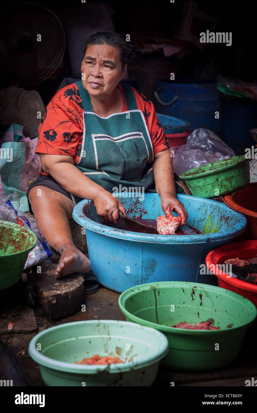 Thailändische Frau schneidet Fleisch auf dem lokalen Markt in Bangkok, Thailand Stockfoto