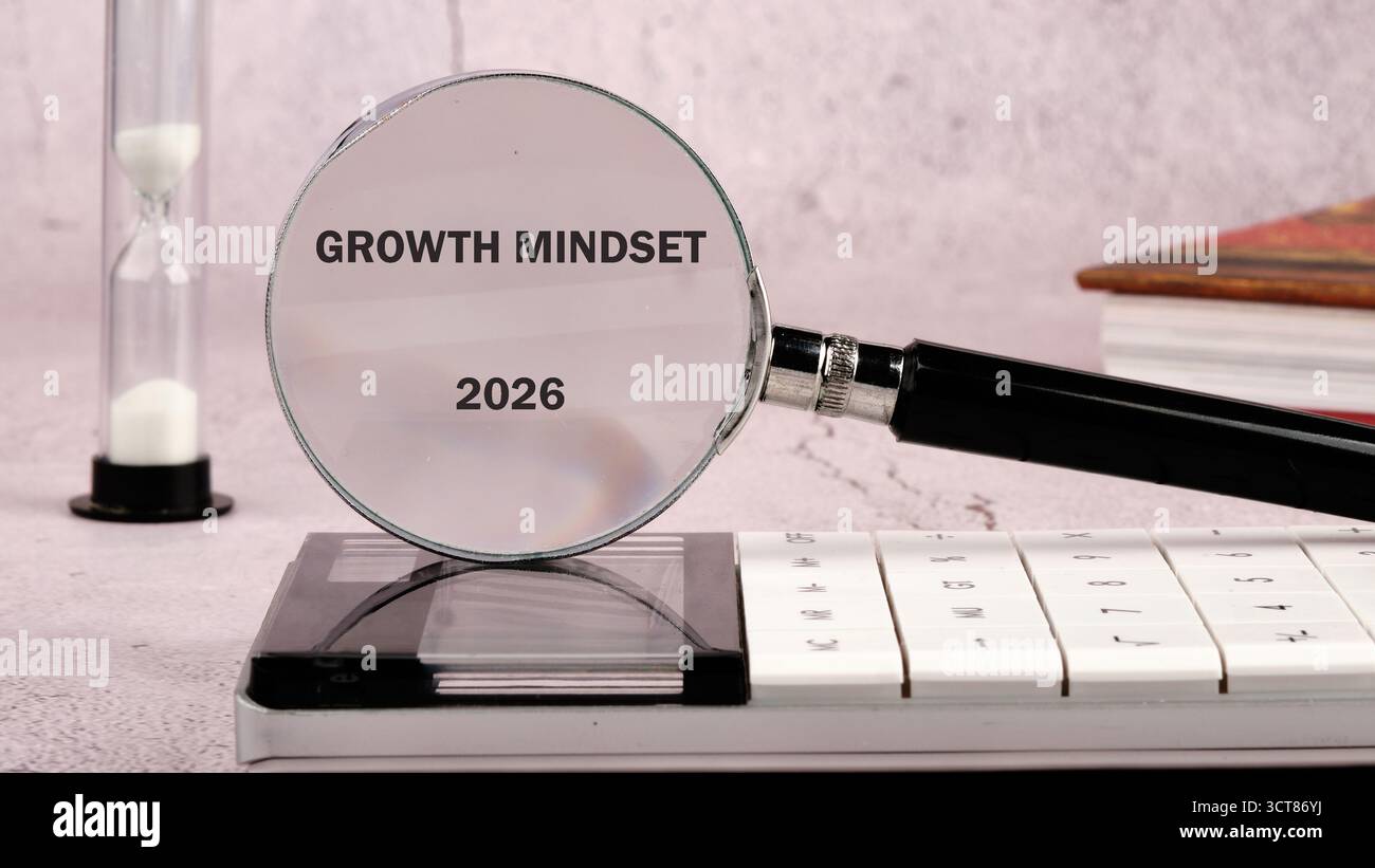 Eine Lupe zeigt den Begriff Growth Mindset 2026. Eine Sanduhr steht neben einem Taschenrechner und einem Stapel Bücher, die alle auf einer strukturierten Oberfläche liegen Stockfoto