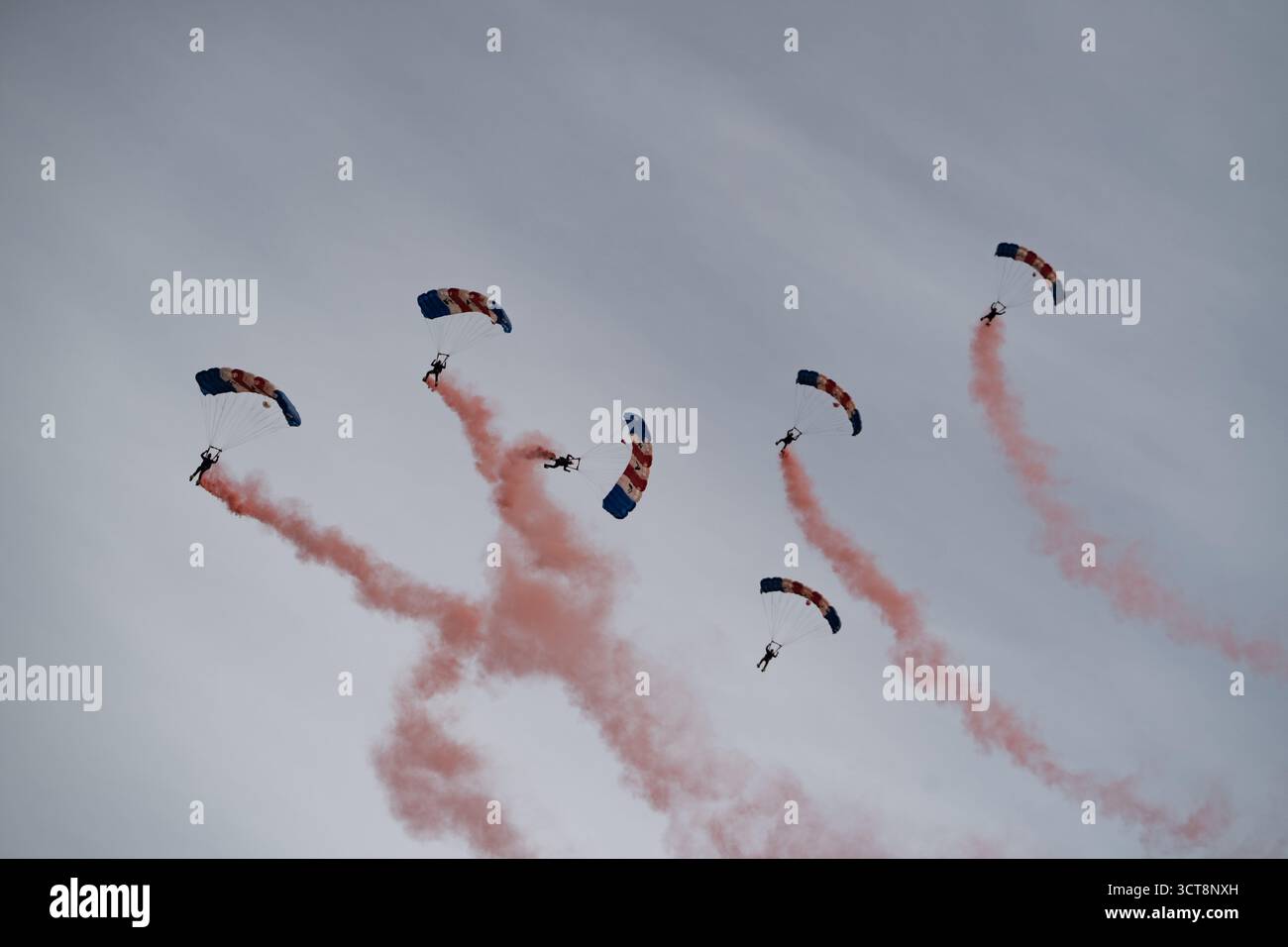 RAF Falcons Fallschirmspringer-Team führt eine Luftdemonstration mit roten Rauchspuren durch Stockfoto