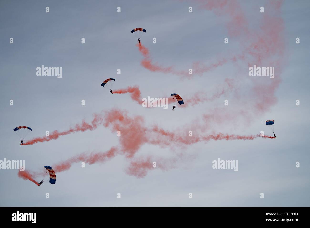 RAF Falcons Fallschirmspringen Team mit roten Rauchspuren auf der Duxford Air Show Stockfoto