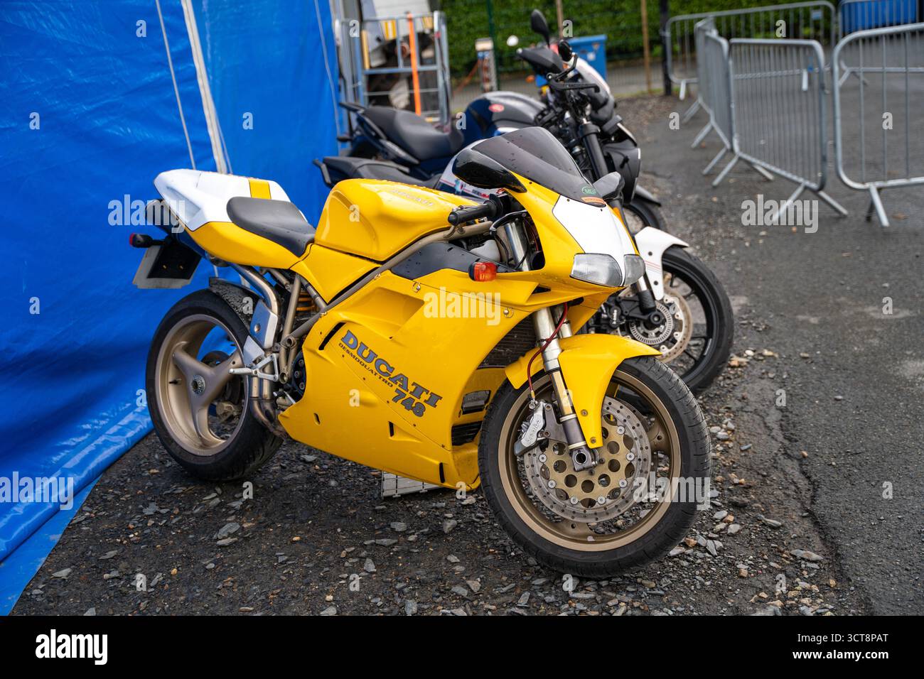 Gelbes Ducati Superbike parkt bei der Isle of man Rennveranstaltung mit Barrieren Stockfoto