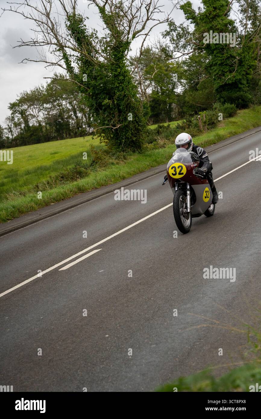 Klassisches Rennmotorrad Nummer 32 auf der Landstraße durch die grüne Landschaft Stockfoto