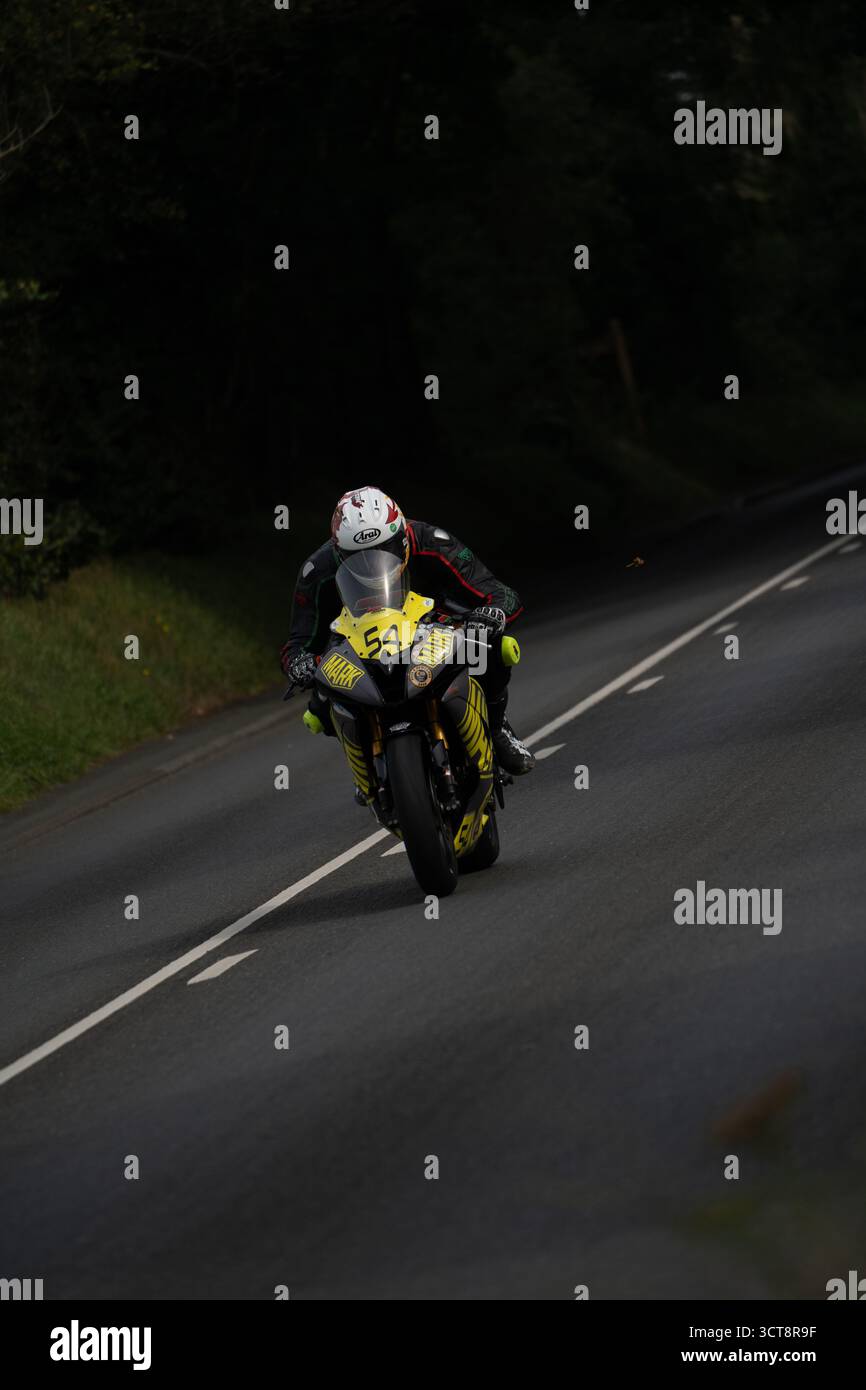 Rennmotorradfahrer Nummer 54 auf Isle of man TT-Kurs in gelber und schwarzer Lackierung Stockfoto