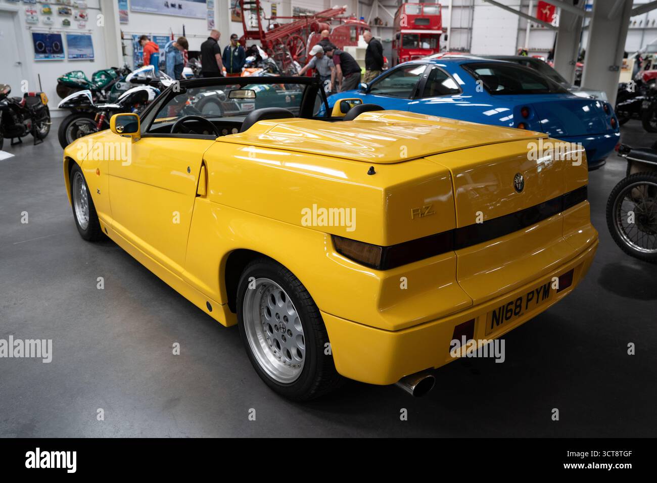 Gelbes Alfa Romeo RZ Cabrio auf Oldtimer-Ausstellung mit Oldtimer-Motorrädern Stockfoto
