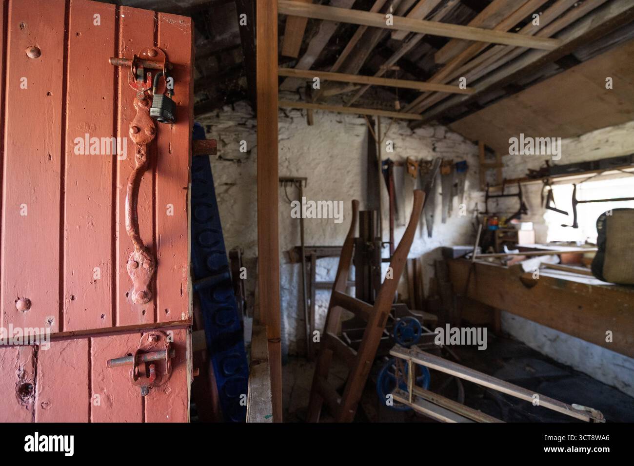 Historisches Mühleninnere mit traditioneller rot lackierter Tür und Holzmaschinen Stockfoto