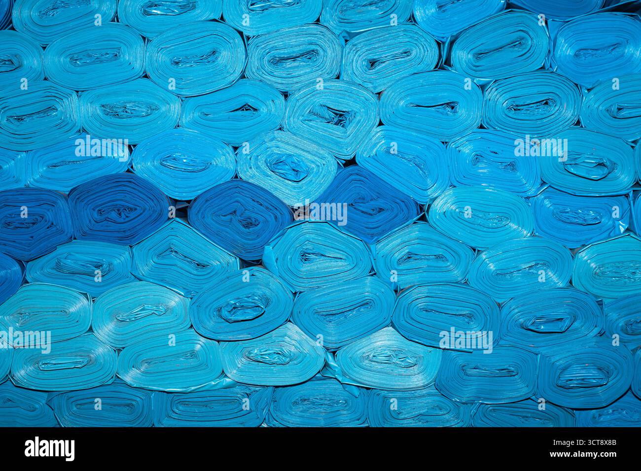 Neue blaue Kunststoffbeutel werden gerollt und übereinander gestapelt. Stockfoto