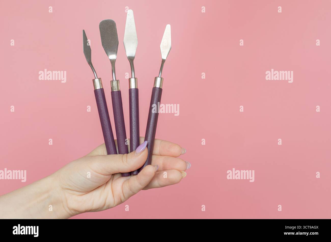 Ein Mädchen hält einen 4Piece Cake Cream Spatel auf rosa Hintergrund. Stockfoto