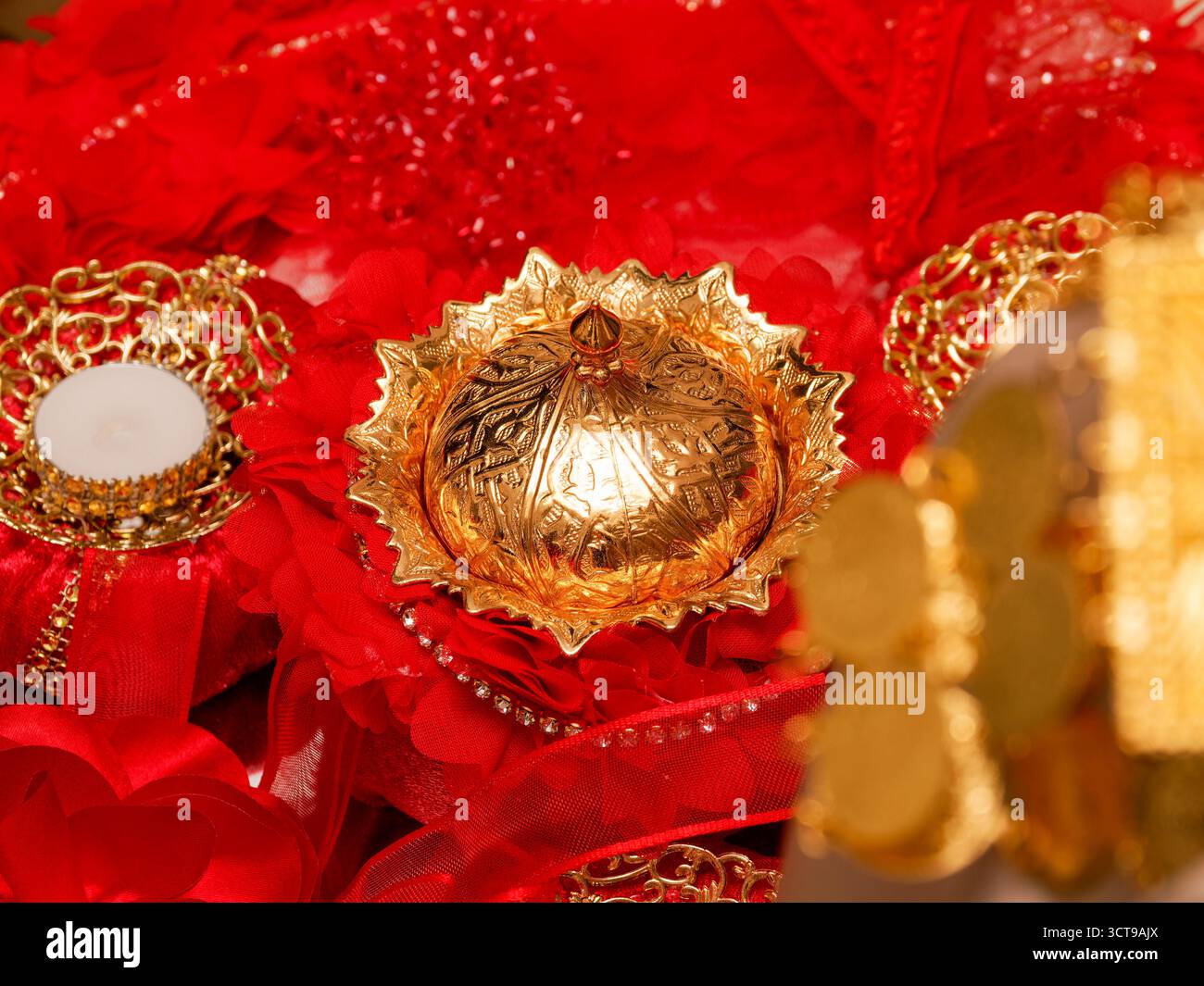 Goldenes orientalisches Zeremonialgericht auf roter Spitze während der traditionellen Hochzeit. Stockfoto
