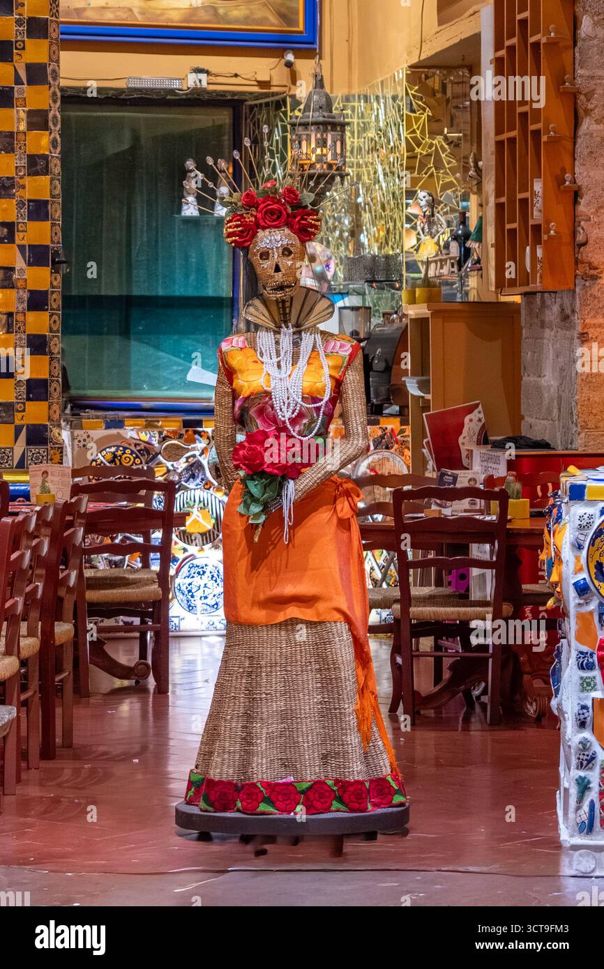 Eine Frau in einem Kostüm mit einer Blume in der Hand steht in einem Raum mit Stühlen und Tischen. Historisches Zentrum von Queretaro, Kolonialarchitektur, d Stockfoto