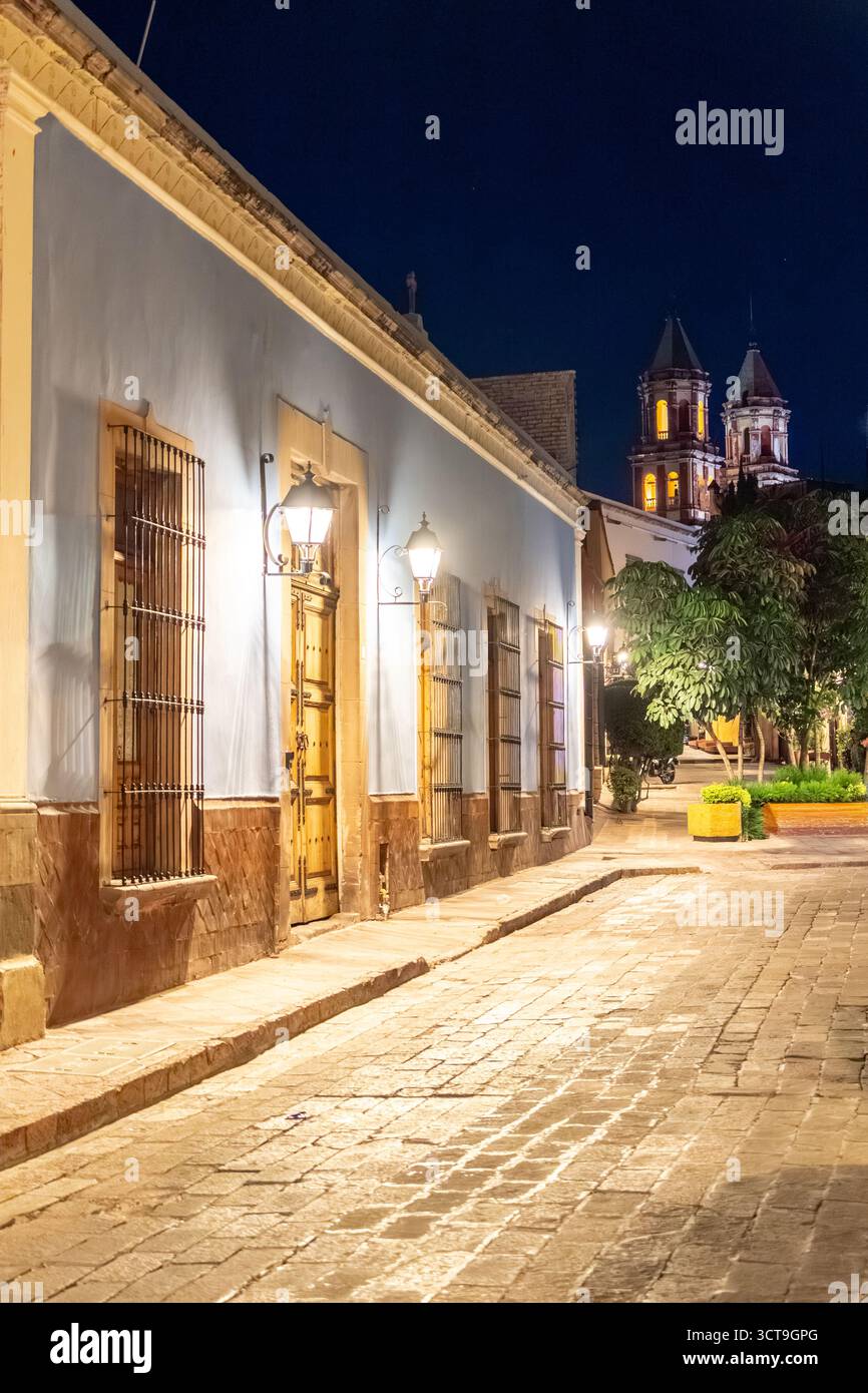 Eine Straße bei Nacht mit einem blauen Gebäude und zwei hohen Türmen. Die Straße ist leer. Historisches Zentrum von Queretaro, Kolonialarchitektur, Dekorationen für Stockfoto