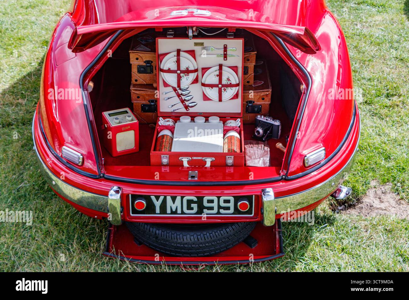 Klassischer roter Bristol-Sportwagen mit offenem Kofferraum, mit einem Vintage-Picknick-Set und Zubehör an einem grasbewachsenen Blyth-Strand Stockfoto