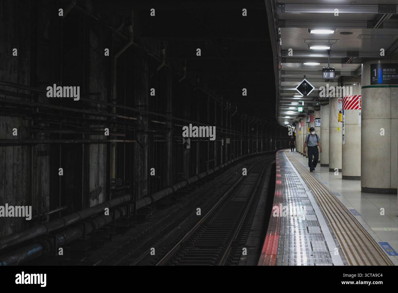 Mann, der auf der hellen Plattform in der U-Bahn-Station Tokio mit starkem Kontrast läuft Stockfoto