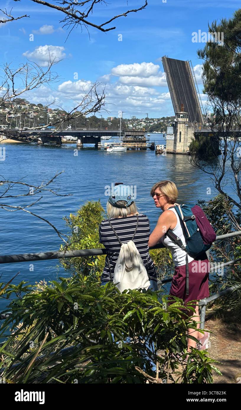 Zwei Frauen beobachten Boote, die durch eine erhöhte Brücke, die Spit, Nord-Sydney, NSW, Australien fahren. Kein MR oder PR - Smartphone-aufgenommenes Stockfoto