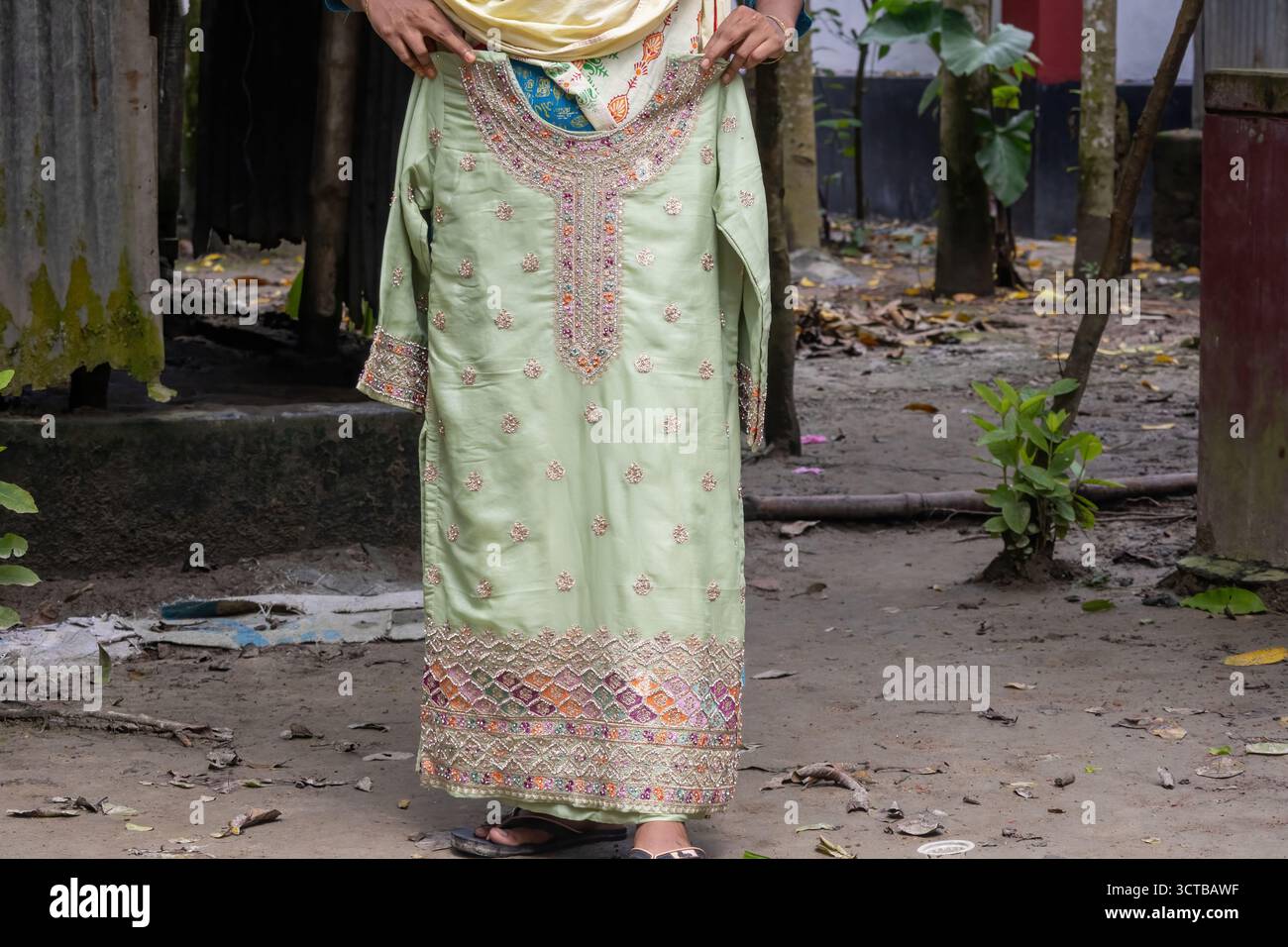 Eine Bangladeschische Frauenhand präsentiert einen hoch verzierten Kameez mit bunten Perlen und Stickereien. Traditionelle südasiatische Mode, ethnische Kleidung und Stockfoto