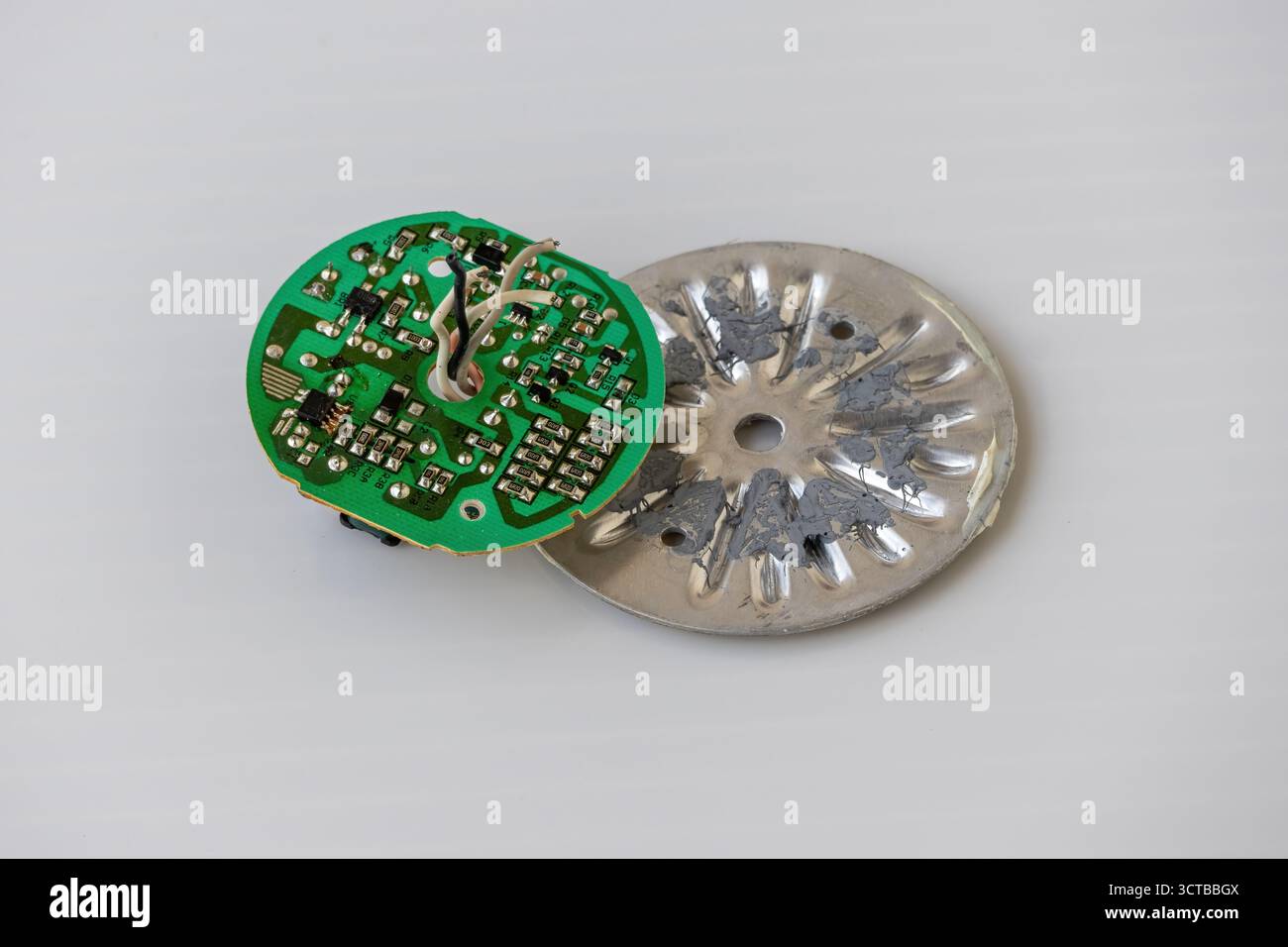 Nahaufnahme einer zerlegten Leiterplatte für wiederaufladbare AC/DC-LED-Glühlampen mit elektronischen Komponenten und Mikrochip. Grüne Leiterplatte, Technologie, Techniker Stockfoto