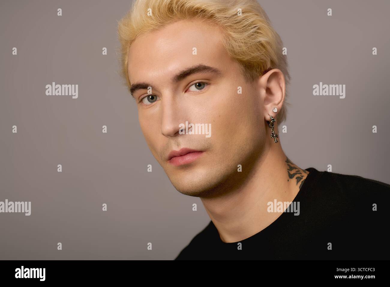 Ein selbstbewusster Teenager zeigt seine auffälligen Details und seinen trendigen Stil vor einem schlichten Hintergrund. Stockfoto