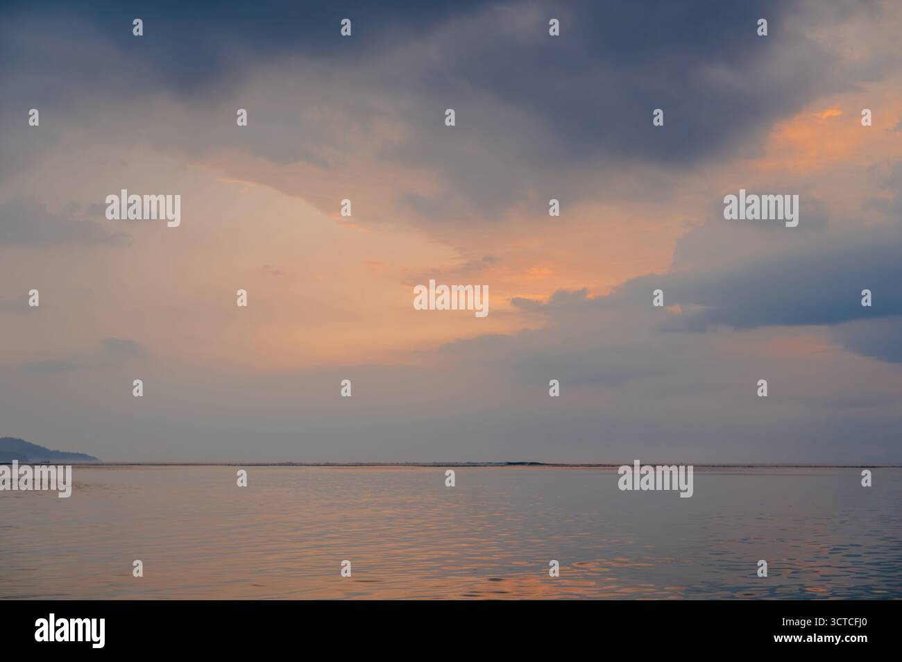 Pastellfarbener Sonnenuntergangshimmel mit orangefarbenen Wolken über dem ruhigen Ozean, Gili Air Stockfoto