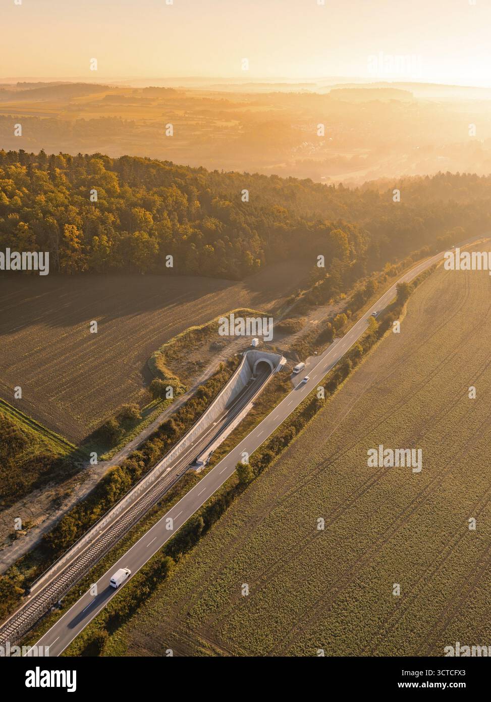 Daemmerungsaufnahme einer laendlichen Landschaft mit Eisenbahn, Strasse und Felder, flankiert von einem Wald, Neubautunnel der Hermann Hessebahn, Calw Stockfoto