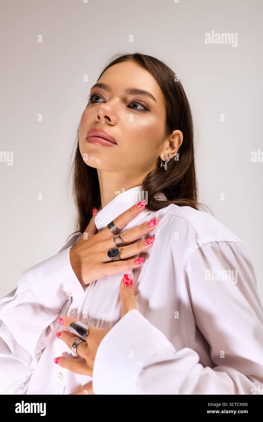 Eine junge Frau posiert anmutig in einem raffinierten Herbstensemble und hebt ihre Schönheit hervor. Stockfoto