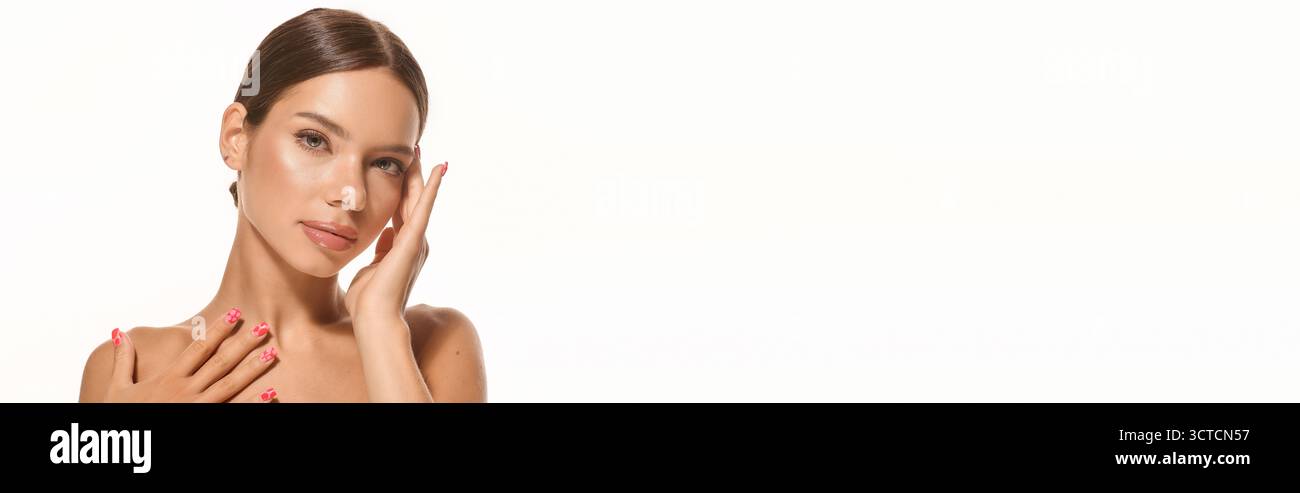 Eine junge Frau posiert sanft und hebt ihr natürliches Make-up und ihr strahlendes Teint hervor Stockfoto