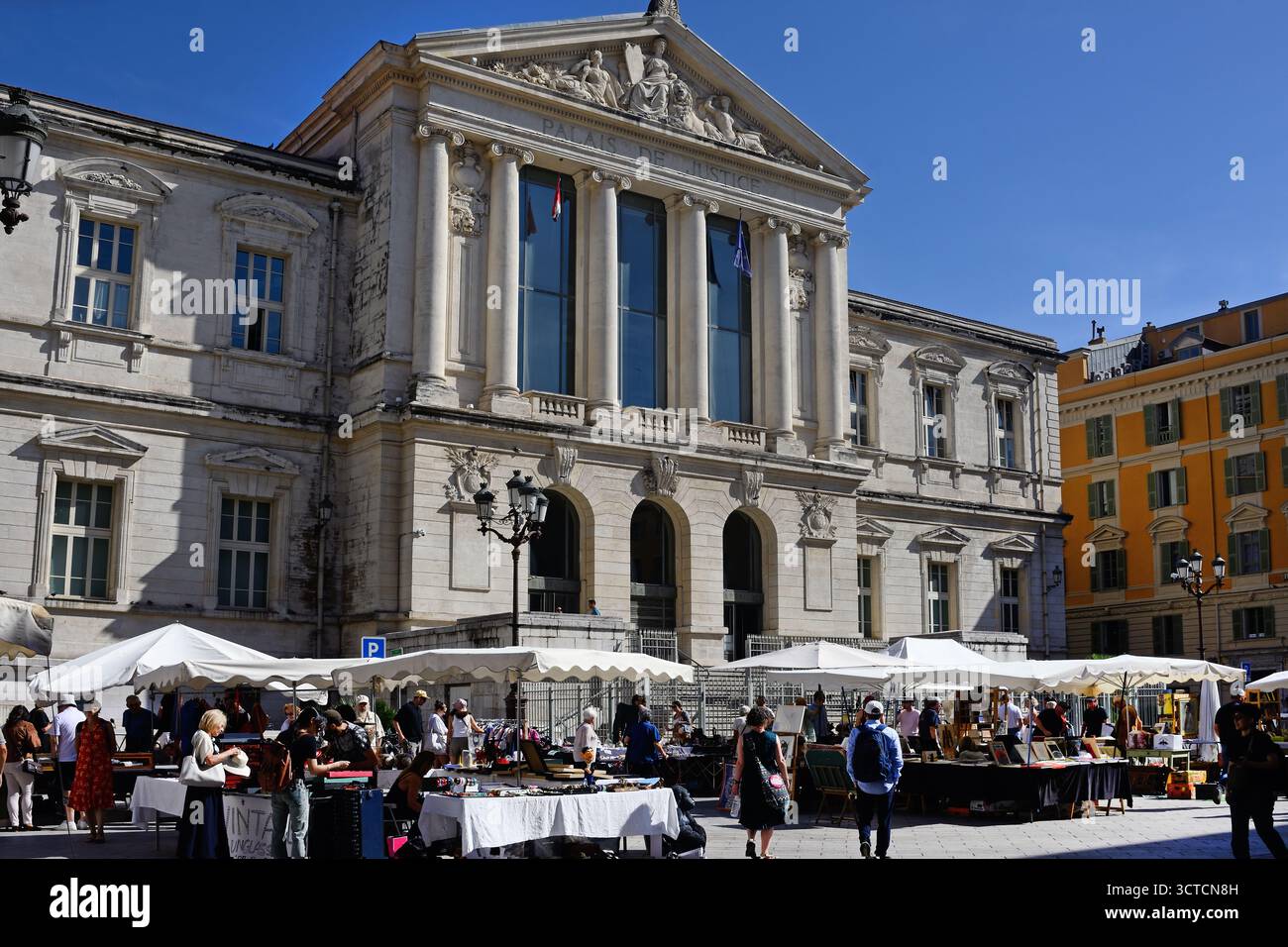 Besucher, die auf einem Straßenmarkt vor dem neoklassizistischen Palais de Justice (Gerichtsgebäude) am Place du Palais, Nizza, Alpes-Maritimes, Stockfoto
