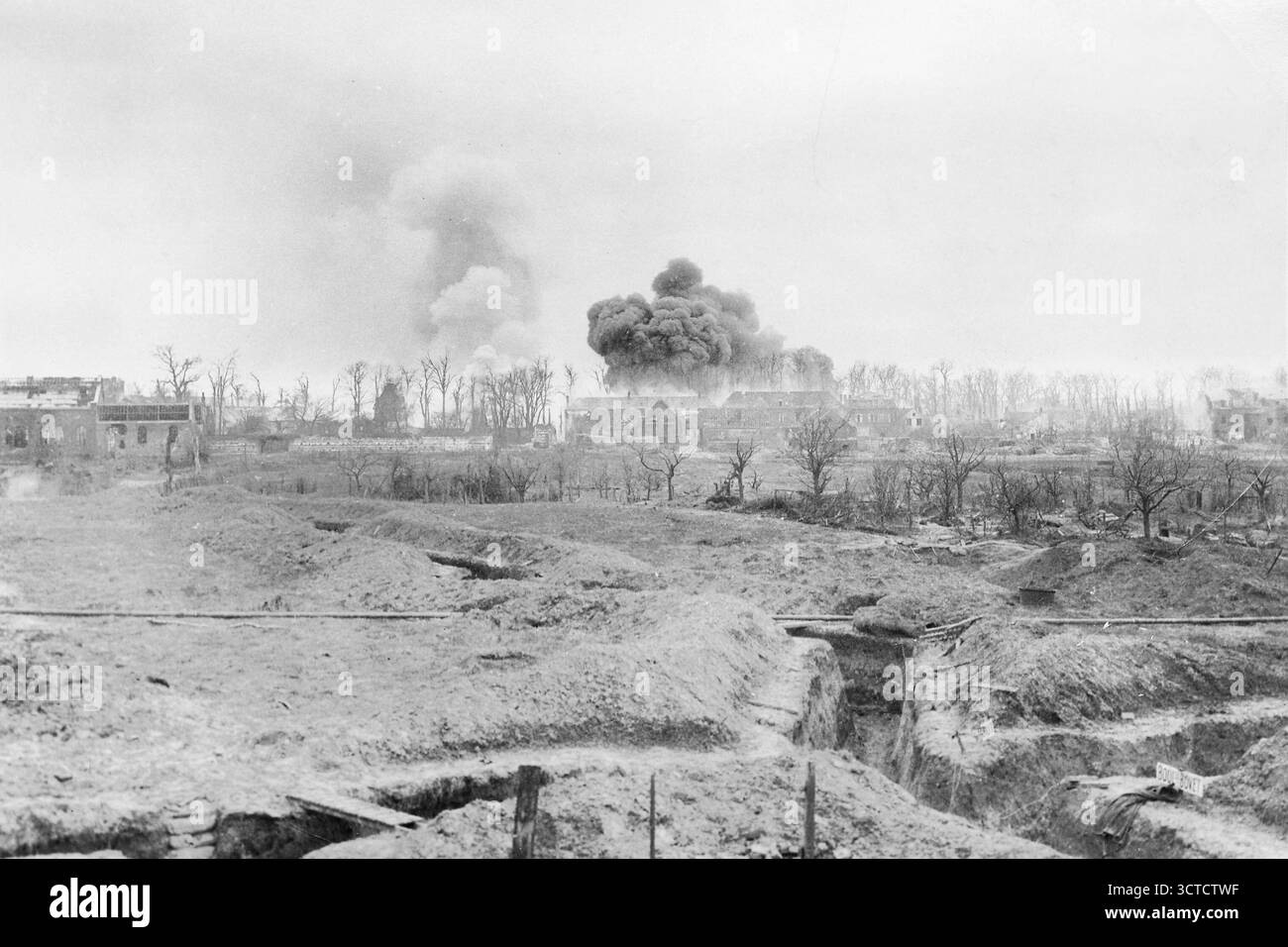 Eine Reihe von Gräben in einer französischen Kriegszone während des Ersten Weltkriegs, wobei Rauch aus Bombenschäden in der Ferne aufsteigt. Die Szene erfasst die Verwüstung und Intensität der Schlacht an der Westfront, wo Städte und Landschaften durch permanentes Schussfeuer und Zerstörung zerstört wurden. Stockfoto