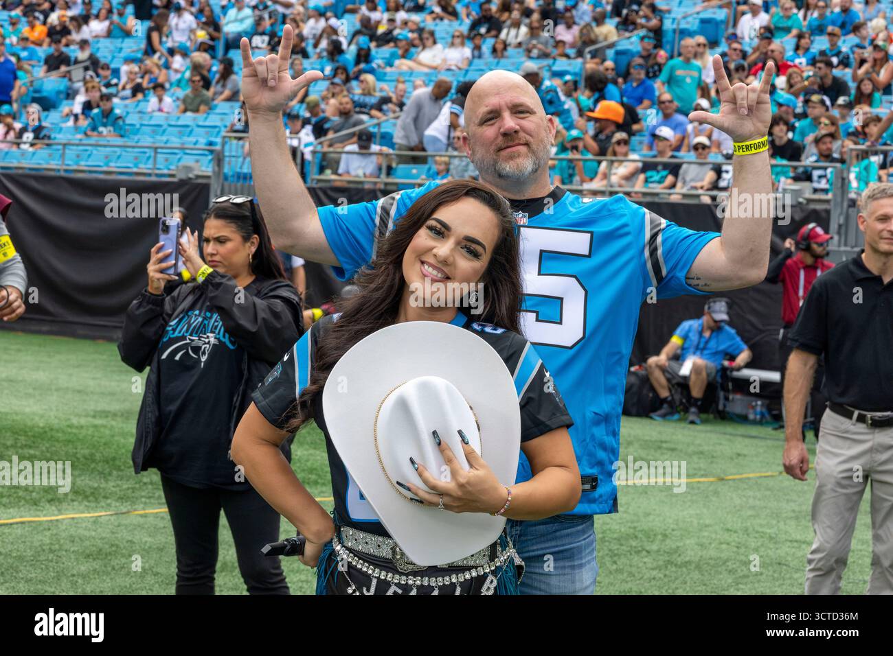 Charlotte, North Carolina, USA. Oktober 2025. Jenny B, gebürtige Tejano-Sängerin aus San Antonio, bereitet sich darauf vor, die Nationalhymne vor dem regulären Spiel der Miami Dolphins und der Carolina Panthers im Bank of America Stadium in Charlotte, NC am 5. Oktober 2025 zu singen. Mr. ROB BUSH, der das Carolina Panthers Trikot Nummer 25 trägt, wird die Nationalhymne während des Auftritts in die American Sign Language (ASL) übersetzen. Die Delfine besiegten die Panthers mit 27:24. (Kreditbild: © Israel Anta via ZUMA Press Wire) NUR REDAKTIONELLE VERWENDUNG! Nicht für kommerzielle ZWECKE! Stockfoto