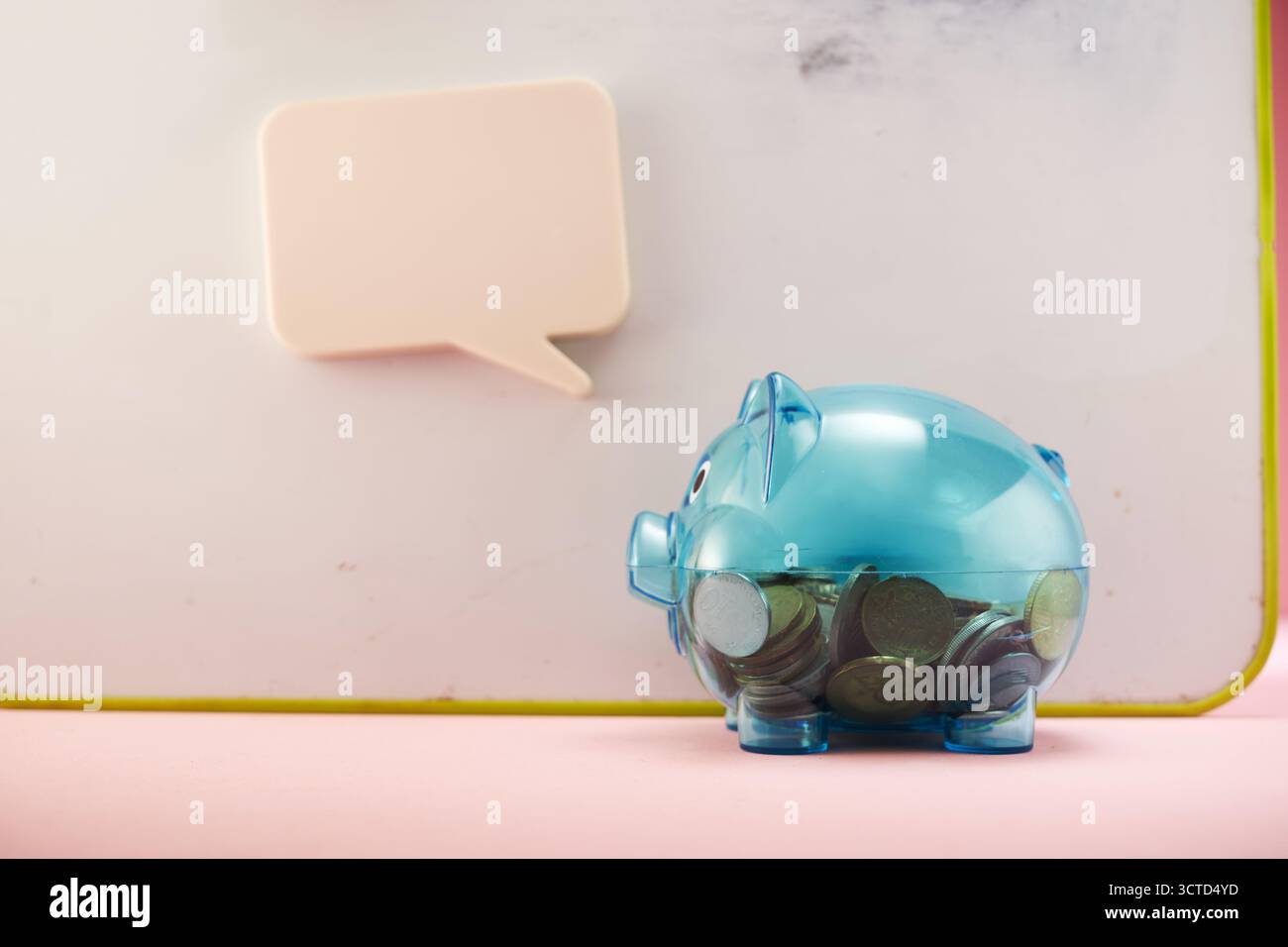 Durchsichtige Schweinebank, gefüllt mit Münzen mit Sprechblase. Stockfoto