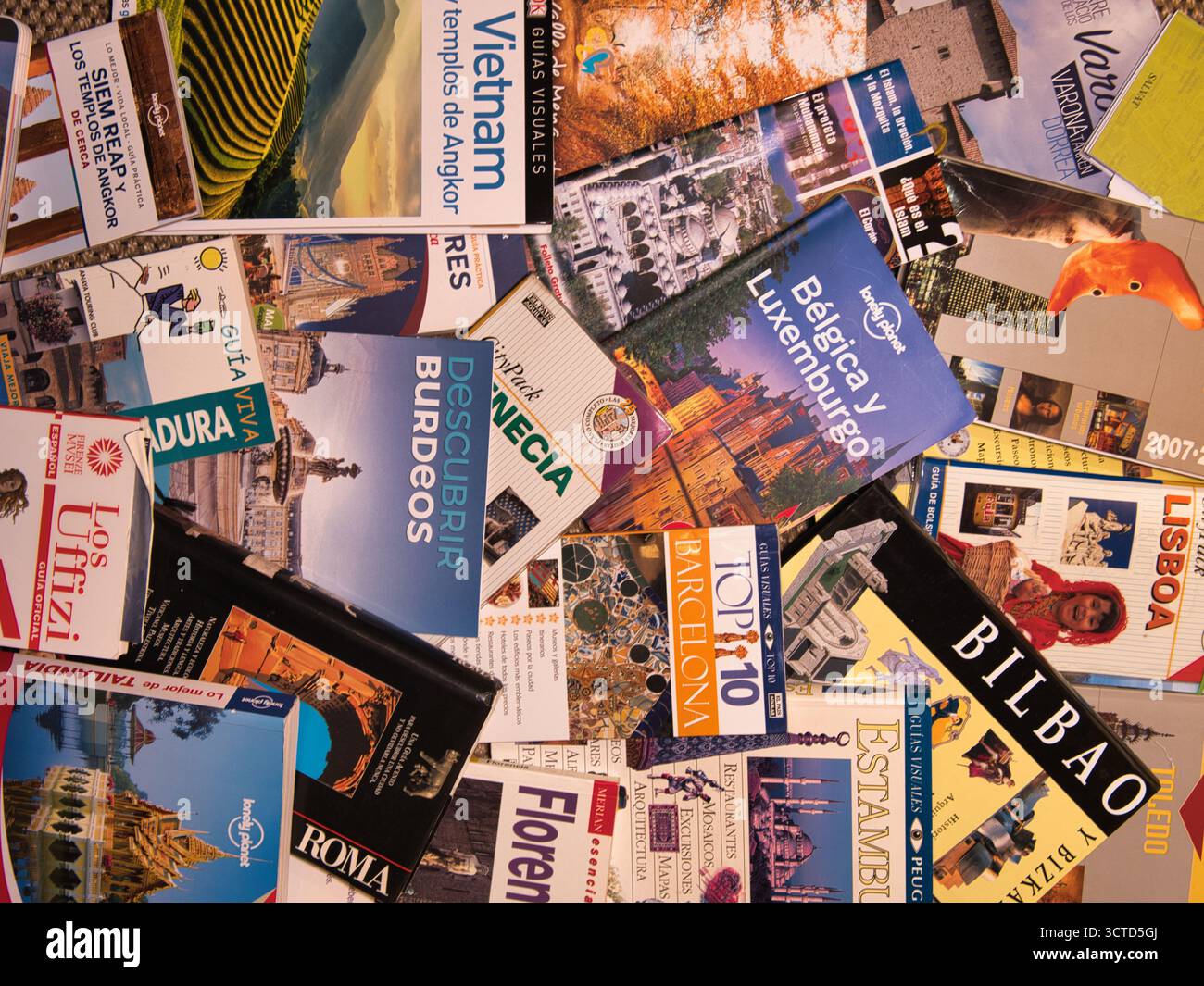 Jumble of International Travel Guide Books - Hochwinkelflaches Lagen verschiedener farbenfroher, verstreuter Reiseführer für europäische und asiatische Städte, Symbolizi Stockfoto