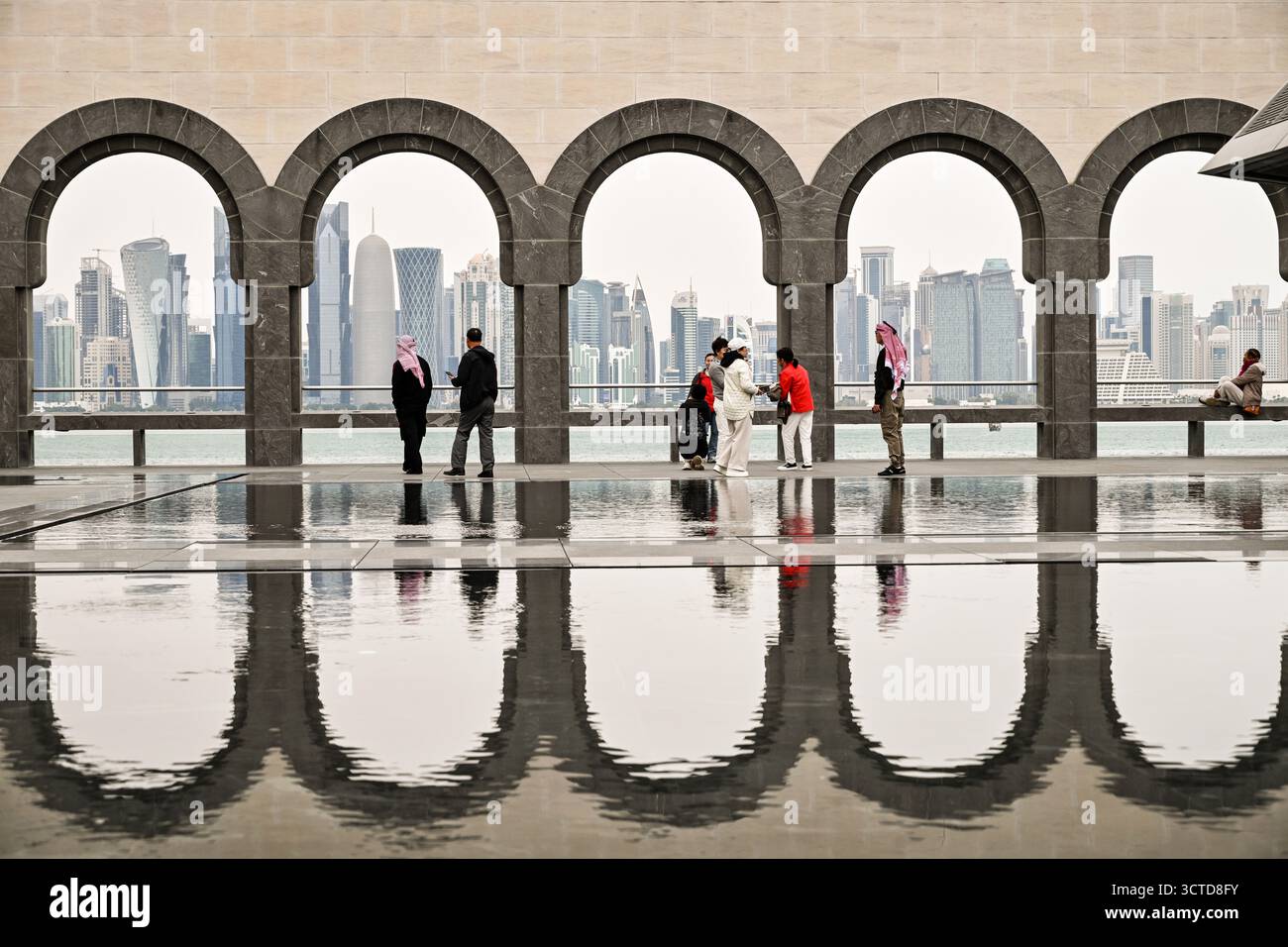 Katar, Doha: Das Museum für islamische Kunst Blick auf die Skyline von West Bay durch die Arkaden. Familienbesucher und Spiegeleffekt Stockfoto