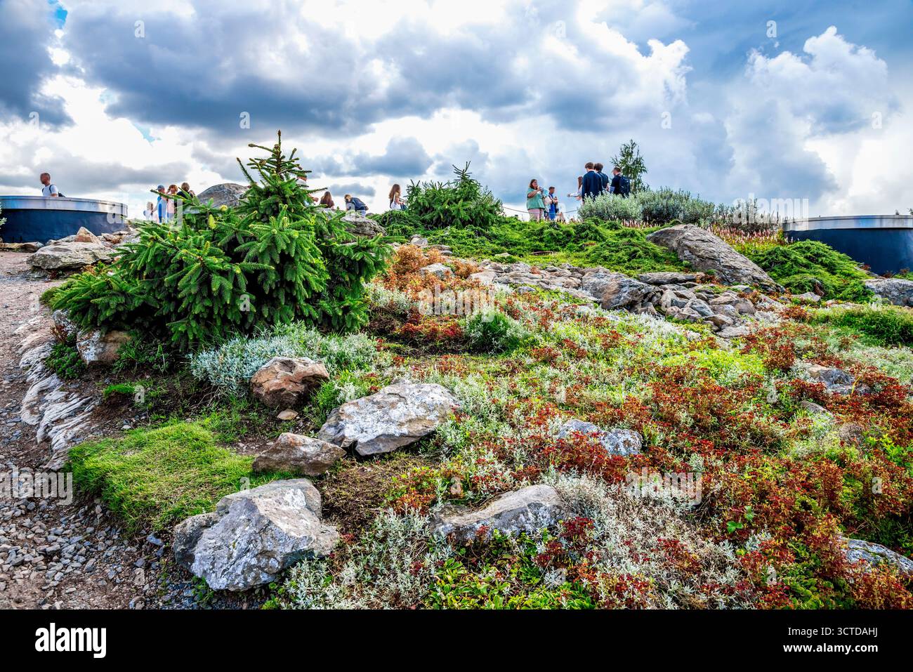 Gruppe von Menschen auf einem felsigen Hügel Garten Aussichtspunkt im Saryadye Park mit Grün, Pflanzen und bewölktem Himmel, Moskau, Russland, August 2025 Stockfoto