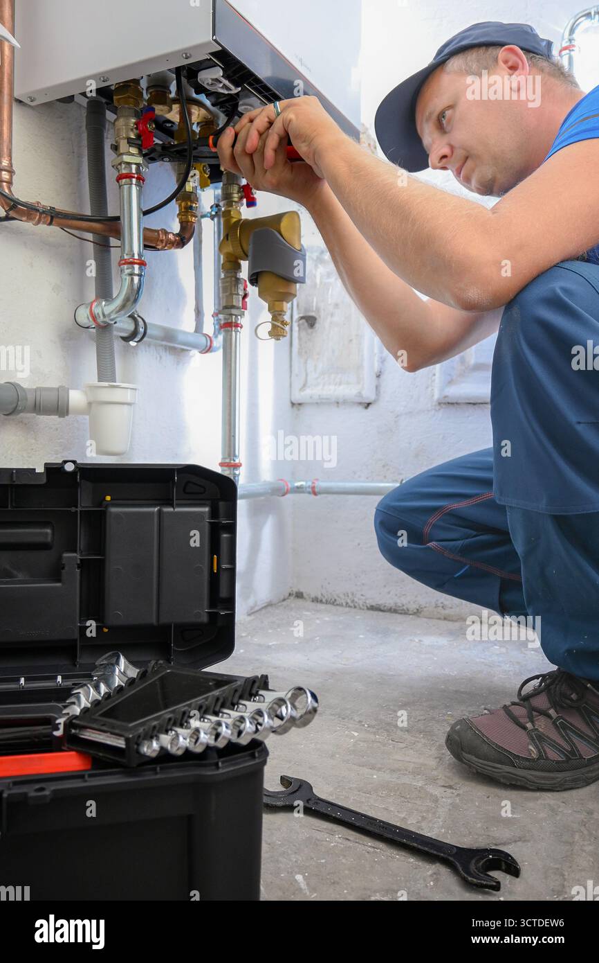 Klempner arbeiten an einem privaten Heizungskessel, führen Wartungs- und Reparaturarbeiten durch. Stockfoto