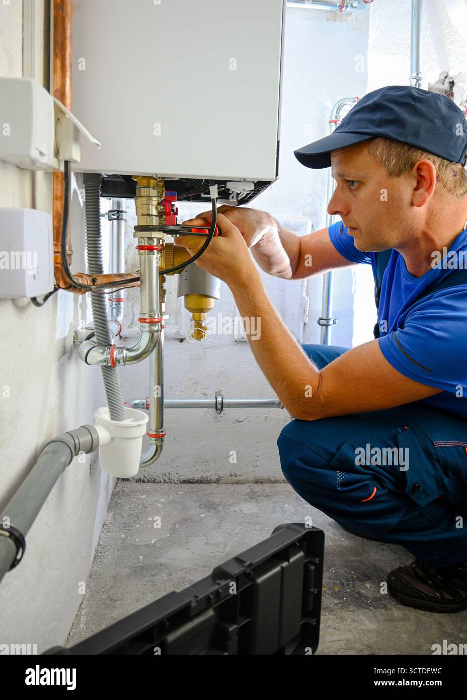 Klempner, der das Heizsystem des Brennwertkessels überprüft. Stockfoto