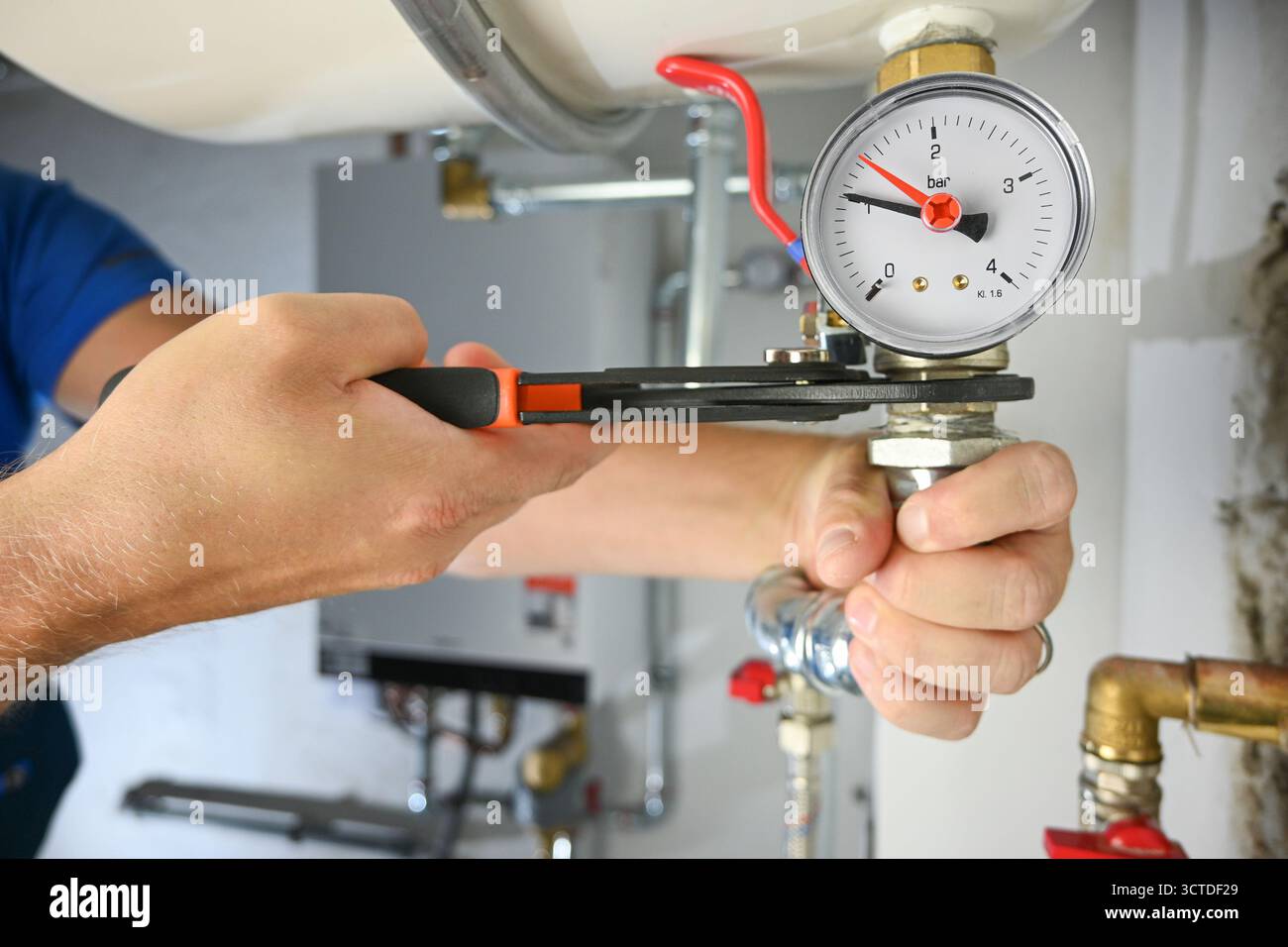 Klempnerhände stellen ein Rohr mit einem Schraubenschlüssel während der Kesselwartung ein. Stockfoto
