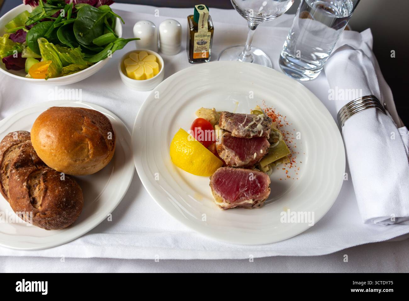 Gebratene Lammlachende mit Salat und Brötchen auf einem Emirates Business Class-Flug Stockfoto