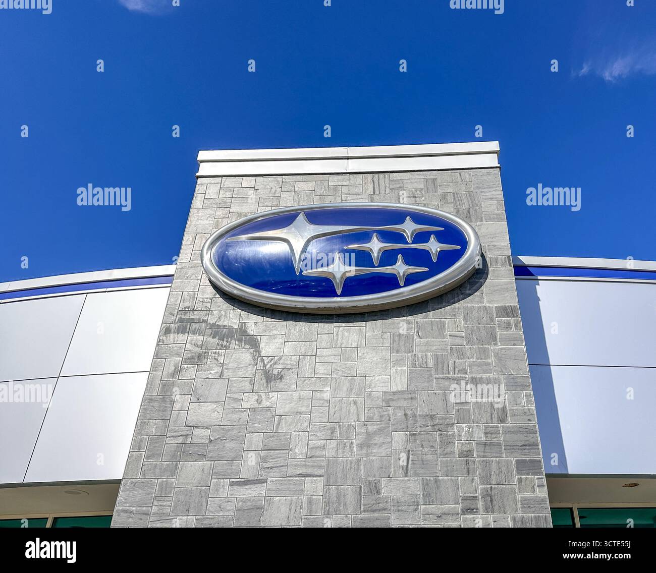 Subaru-Emblem auf der Außenseite eines Händlergebäudes vor blauem Himmel - Smartphone-aufgenommenes Stockfoto