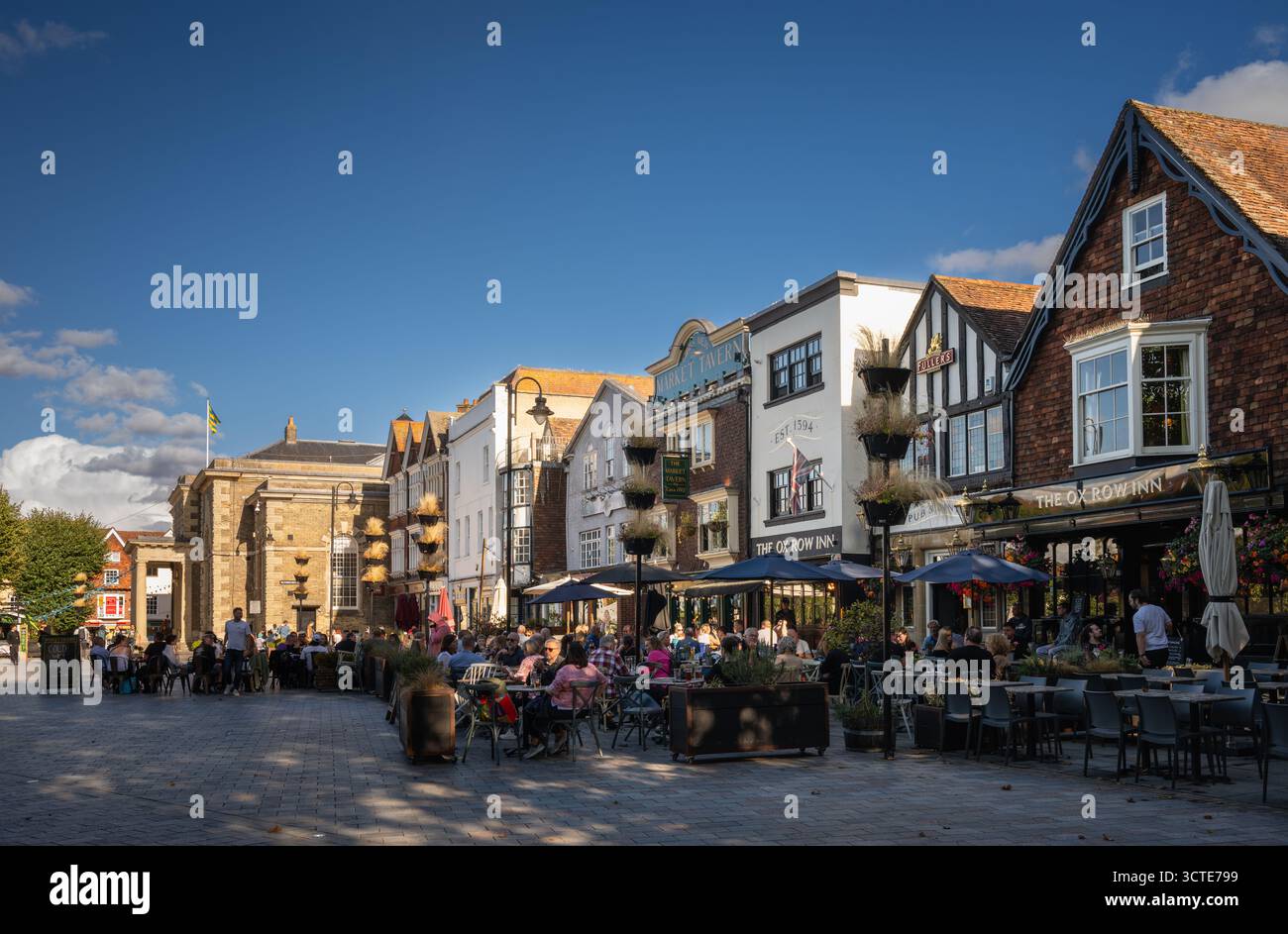 Salisbury, Wiltshire, Vereinigtes Königreich: Der Marktplatz im Zentrum von Salisbury mit Ox Row und Guildhall. Die Leute sitzen vor den lokalen Pubs und genießen einen Drink Stockfoto