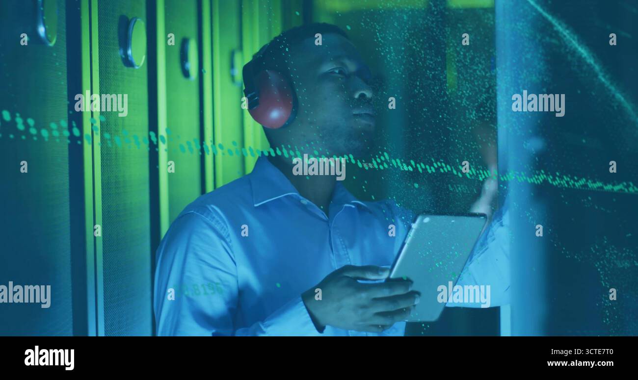 IT-Profi in blauem Hemd, roten Kopfhörern, die LED-Server-Racks mithilfe eines Tablets im Rechenzentrum scannen Stockfoto