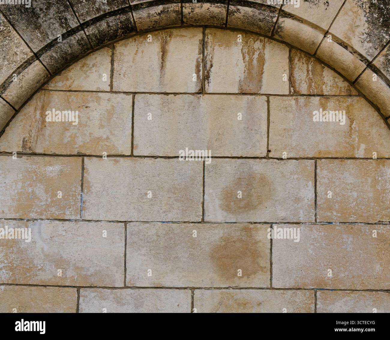 Nahaufnahme einer alten Steinmauer mit bogenförmigem Mauerwerk, mit verwitterten Texturen, Flecken und Zeichen der Zeit, die die Ausdauer und darstellen Stockfoto