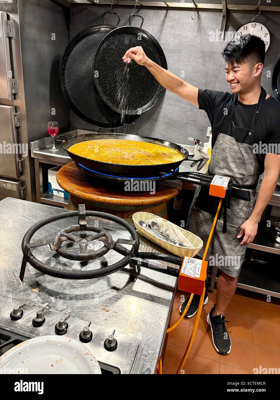 Spanischer Kochkurs in Barcelona, Koch und Lehrer streuen Salz auf das Kochpaellagericht, Spanien, Europa - Smartphone-aufgenommenes Stockfoto