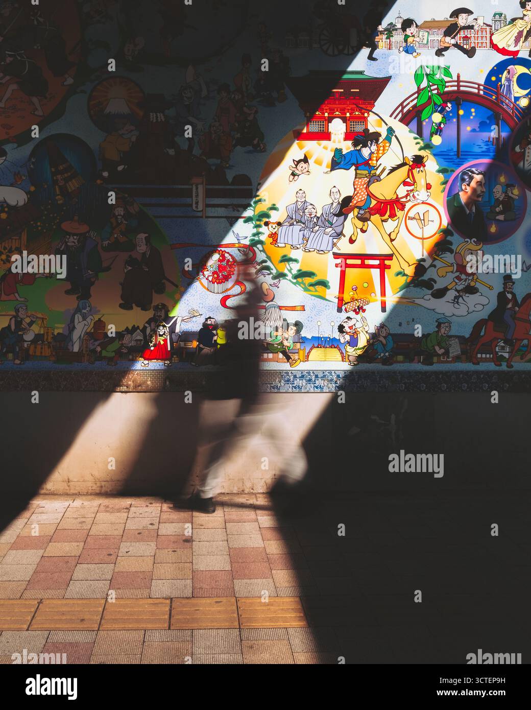 Takadanobaba, Japan - 10. März 2025: Blick auf das Wandbild der Tezuka Productions, das in Licht und Schatten getaucht ist und eine Silhouette gegen das lebendige Kunstwerk wirft. Stockfoto