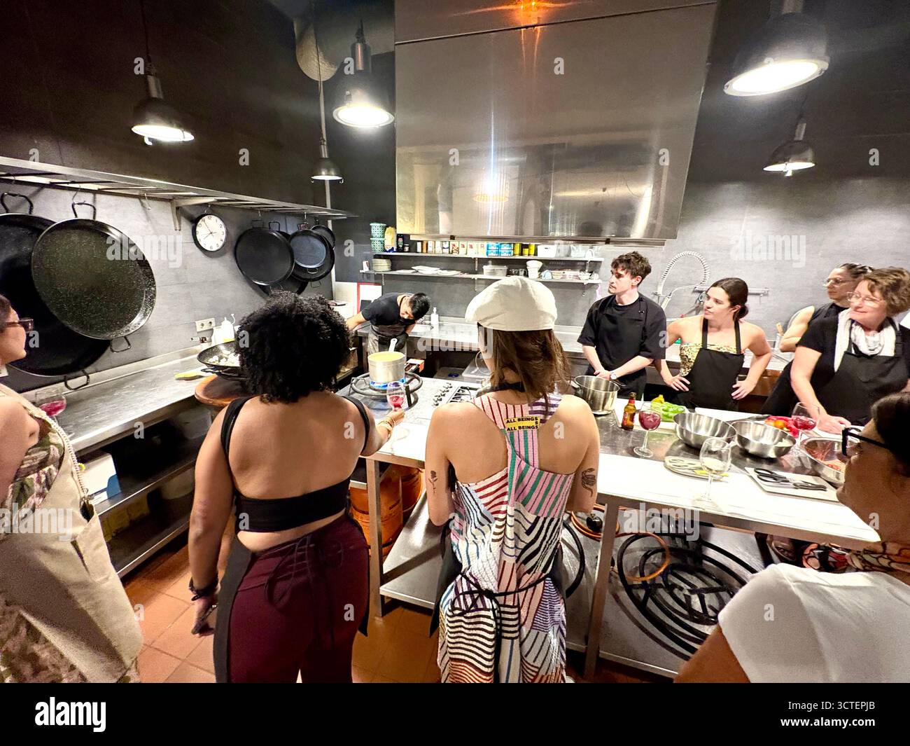 Barcelona Paella Kochkurs, Teilnehmer beobachten, wie der Cheflehrer Koch- und Vorbereitungsaufgaben für die Paella organisiert, Spanien, Europa - Smartphone-aufgenommenes Stockfoto