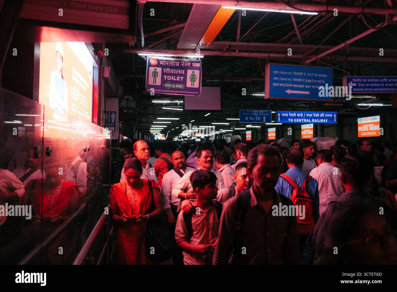 Mumbai, Indien - 23. September 2025: Blick auf einen belebten Bahnsteig voller Pendler unter dem warmen Licht der Deckenleuchten. Stockfoto