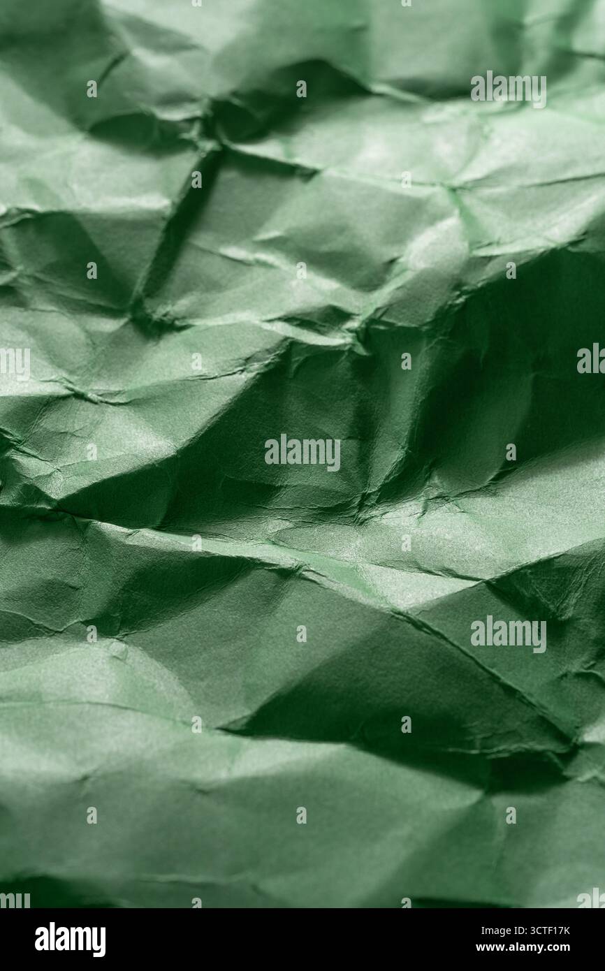 Grüner gefalteter, zerknitterter Papierhintergrund mit geschliffener Textur Stockfoto