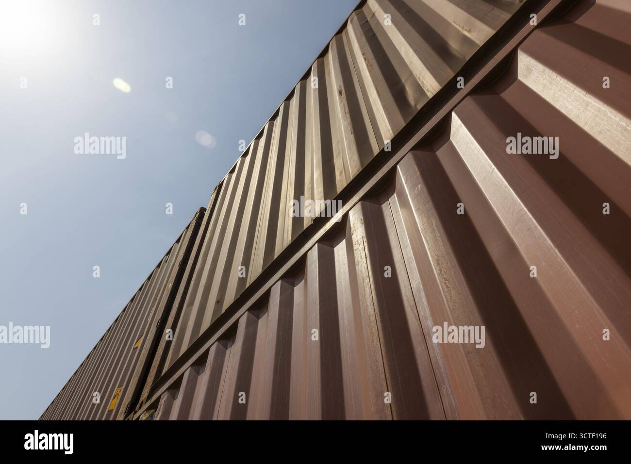 Suswa, Kenia - 05. August 2025: Blick auf hoch aufragende, gewellte Metallbehälter unter einem hellen, wolkenlosen Himmel, deren Oberflächen das Sonnenlicht in scharfen Kontrasten von Licht und Schatten reflektieren. Stockfoto