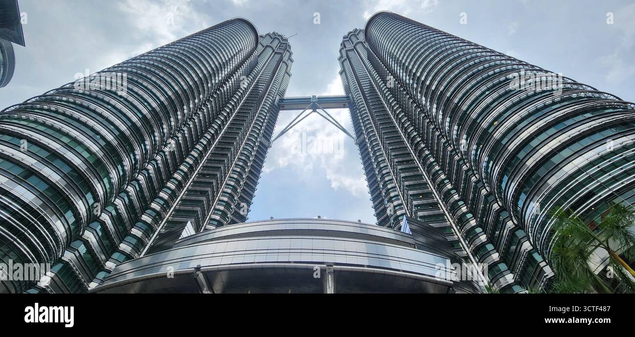 Ein flacher Blick auf zwei Wolkenkratzer vor einem bewölkten Himmel mit moderner Architektur. Malaysia, Kuala Lumpur Stockfoto