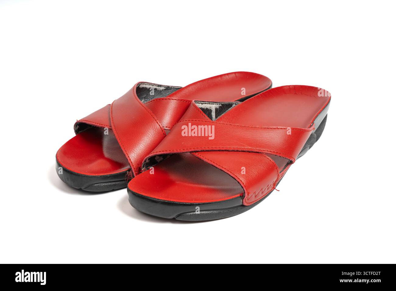 Paar rote Ledersandalen mit Kreuzriemen auf isoliertem weißem Hintergrund. Nahaufnahme von Sommerschuhen mit Crosscross-Design Stockfoto