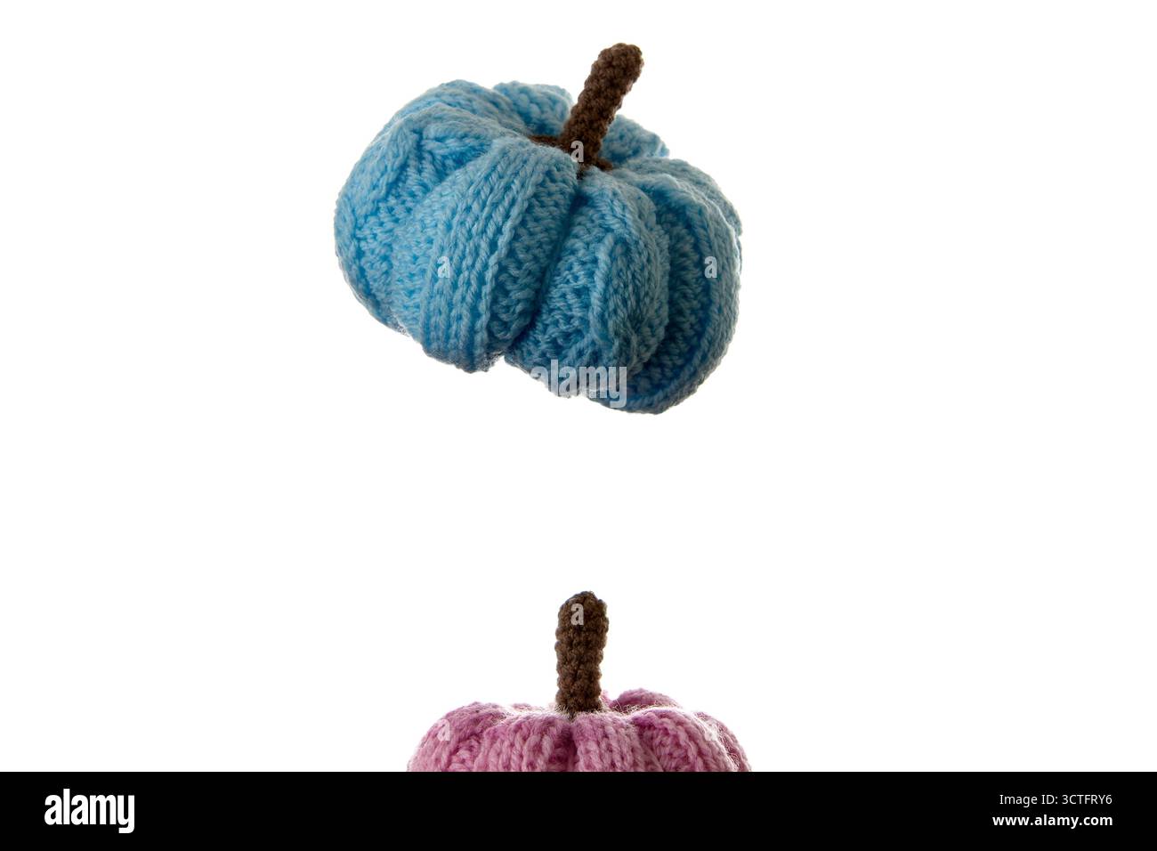 Ein handgefertigter blauer gestrickter Kürbis, isoliert auf weißem Hintergrund, fotografiert mit weichem Licht. Perfekt für gemütliche Herbstdekoration, DIY-Projekte und Bastelarbeiten Stockfoto