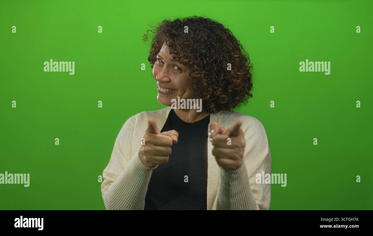 Eine hispanische Frau mittleren Alters zeigt mit den Zeigefingern direkt auf die Kamera auf dem grünen Bildschirm des Studios; Ermutigung. Stockfoto